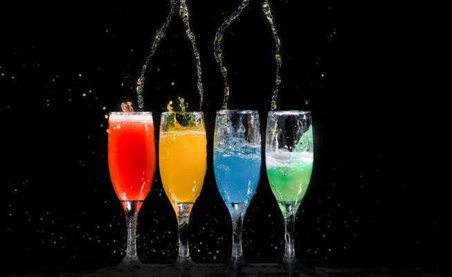 Four champagne flutes in red orange blue and green
