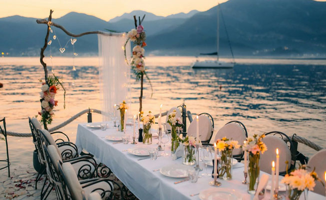 long table with table cloth, flowers, and candles against sea
